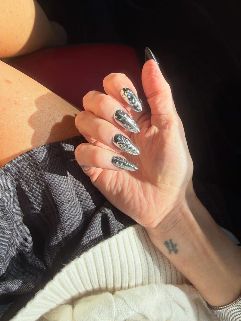 A hand wearing silver chrome Rave Nailz press-on nails